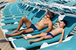 © Andrii - A young athletic man and his son are smiling happily and sunbathing on a sun lounger on a sunny day at the hotel. Happy family vacation at a hotel in the resort. Summer holidays and tourism.