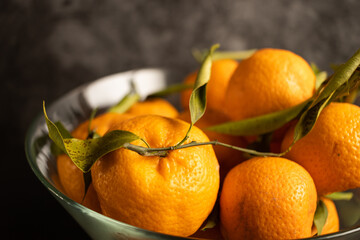 Wall Mural - A bowl of tangerines with leaves on a wooden table