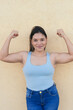 © Hector Pertuz - Latin woman with unshaven armpits flexing arms confidently and looking at camera.