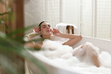 Wall Mural - Beautiful young woman taking bubble bath at home