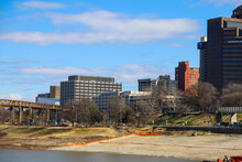 Skyscrapers And Office Buildings Along The Banks Of The Wolf Creek Harbor With Bare Winter Trees And Yellow Winter Grass With Blue Sky And Clouds At Mud Island Park In Memphis Tennessee USA