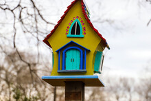 A Yellow, Red, Green And Blue Bird House Surrounded Gray Sky And Bare Winter Trees At Memphis Botanic Garden In Memphis Tennessee USA