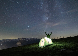 Wall Mural - A stunning view of a starry night with a tourist on the mountain on the foreground