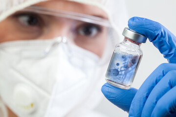 Female doctor or lab scientist holding glass ampoule vial with Coronavirus