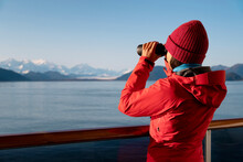 Alaska Glacier Bay Cruise Ship Passenger Looking At Alaskan Mountains With Binoculars Exploring Glacier Bay National Park, USA. Woman On Travel Inside Passage Enjoying View. Vacation Adventure