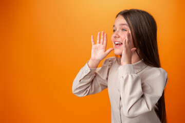 Teenager girl screaming news on orange studio background