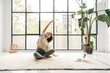 © Daniel - Young woman doing stretching exercises at home following online fitness video with laptop. Copy space.