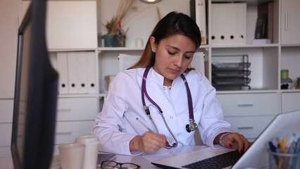 Wall Mural - Woman doctor in medical mask is working at laptop in clinic. High quality FullHD footage