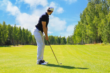 Full length of golf player playing golf on sunny day. Professional male golfer taking shot on golf course.