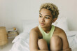 © shurkin_son - Crop shot of pensive African ethnicity teenage girl on bed in stylish minimalistic interior with her arms around legs, looking aside, having thoughtful face expression. People and feelings concept