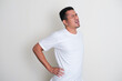 Adult Asian man wearing white plain tshirt suffer low back pain