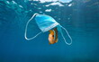 Fish under a surgical face mask, plastic pollution underwater in the ocean, Coronavirus waste COVID-19 pandemic
