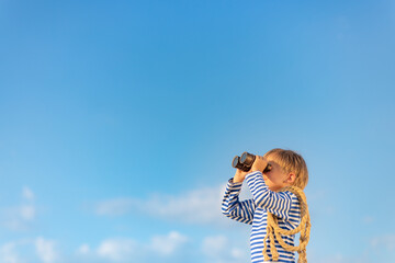 Wall Mural - Happy child looking through vintage binoculars against blue sky.