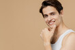 © ViDi Studio - Attractive smiling happy young man 20s perfect skin in undershirt look camera prop up chin isolated on pastel pastel beige background studio portrait. Skin care healthcare cosmetic procedures concept.