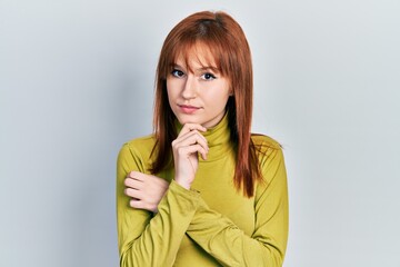 Poster - Redhead young woman wearing turtleneck sweater thinking concentrated about doubt with finger on chin and looking up wondering