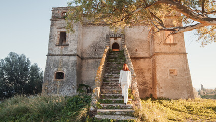 Beautiful girl in white dress enters an ancient castle in the countryside 