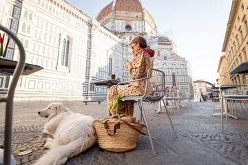 Wall Mural - Woman sitting with her dog on cafe terrace near famous Duomo cathedral in Florence. Concept of traveling italian landmarks, friendship with dog and italian lifestyle