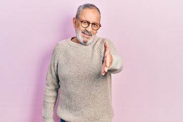 Sticker - Handsome senior man with beard wearing casual sweater and glasses smiling friendly offering handshake as greeting and welcoming. successful business.