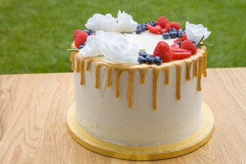 Canvas Print - A closeup of a delicious cake decorated with white flowers and berries.