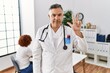 © Krakenimages.com - Middle age doctor man at the clinic with a patient showing and pointing up with fingers number three while smiling confident and happy.