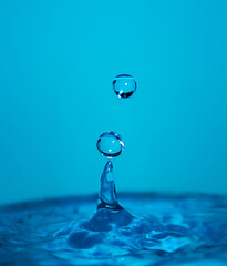 Wall Mural - Falling drops of water on a blue background. Water splash.