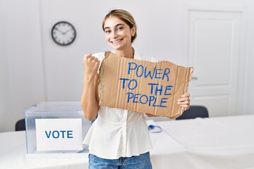 Sticker - Young blonde woman at political election holding power to the people banner screaming proud, celebrating victory and success very excited with raised arms