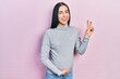 © Krakenimages.com - Beautiful woman with blue eyes expecting a baby, touching pregnant belly smiling looking to the camera showing fingers doing victory sign. number two.