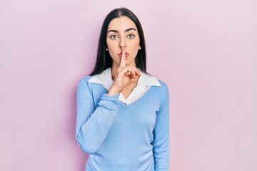 Poster - Beautiful woman with blue eyes standing over pink background asking to be quiet with finger on lips. silence and secret concept.