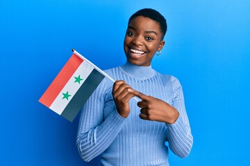 Sticker - Young african american woman holding syria flag smiling happy pointing with hand and finger