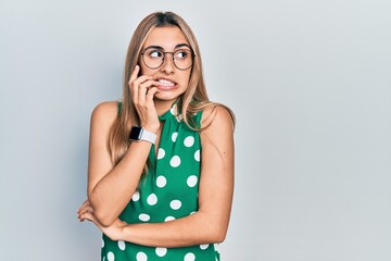 Poster - Beautiful hispanic woman wearing elegant shirt and glasses looking stressed and nervous with hands on mouth biting nails. anxiety problem.