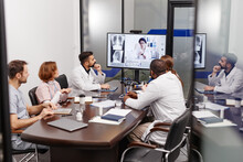 Large Group Of Multi-ethnic Medical Experts In Lab Coats Listening To Their Colleague Sharing New Information During Online Meeting