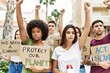 © Krakenimages.com - Group of young activists people protesting with fists raised up standing at the city.