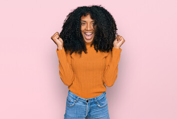 Wall Mural - Young african american girl wearing casual clothes celebrating surprised and amazed for success with arms raised and open eyes. winner concept.