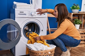 Canvas Print - Middle age woman smiling confident washing clothes at laundry room