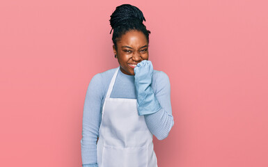 Wall Mural - Young african american woman wearing apron looking stressed and nervous with hands on mouth biting nails. anxiety problem.