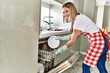 © Krakenimages.com - Young caucasian girl smiling happy whashing dishes using dishwasher at the kitchen.
