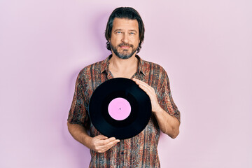 Sticker - Middle age caucasian man holding vinyl disc relaxed with serious expression on face. simple and natural looking at the camera.