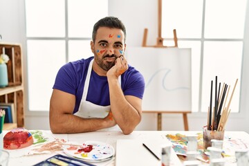 Canvas Print - Young hispanic man with beard at art studio with painted face thinking looking tired and bored with depression problems with crossed arms.