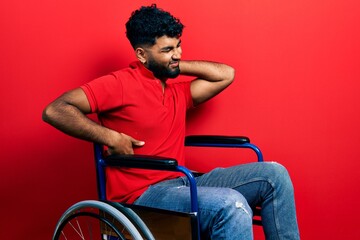 Poster - Arab man with beard sitting on wheelchair suffering of neck ache injury, touching neck with hand, muscular pain