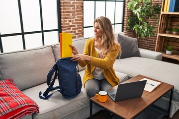 Young blonde woman smiling confident studying at home