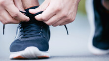 Cropped View Of Sportsman Tying Shoelaces On Sneaker