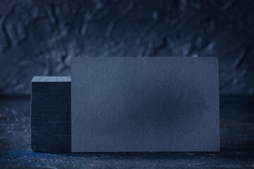 Wall Mural - Black business card mock-up on a black slate background, a template for design presentation, thick cardboard