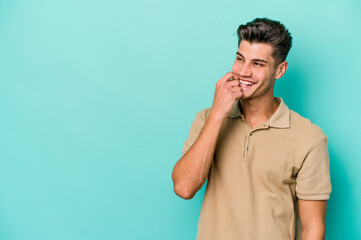 young caucasian man isolated on blue background relaxed thinking about something looking at a copy s