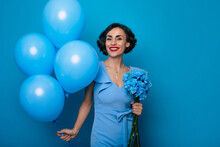 International Women's Day. Mothers Day. St. Valentine's Day. Lovely Happy Woman In A Blue Dress Holds A Bunch Of Spring Flowers And Balloons, That She Is Given In Her Hands From Her Beloved.