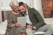 © PoppyPix - modern pensioner lady cuddling and comforting his middle-aged son while watching videos on her tablet. High quality photo