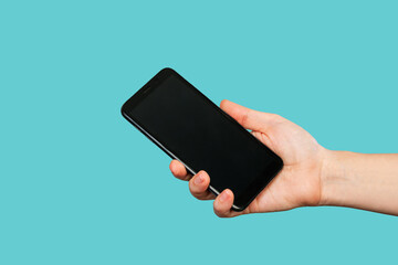 Mobile phone with black screen in female hand isolated on a trendy blue background. Blank with an empty copy space for the text. Template for the design. Mockup of a smartphone
