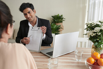 Wall Mural - smiling insurance agent showing form to senior woman and explaining how to fill it to get property i