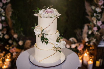 night wedding ceremony, the arch is decorated with flowers, candles and garlands of light bulbs and there is a wedding cake on the table