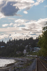 a view down a set of train tracks with a train approaching in the distance blue sky white clouds t