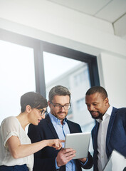 Poster - Teamwork and technology - invaluable business assets. Shot of a team of colleagues using a digital tablet together at work.